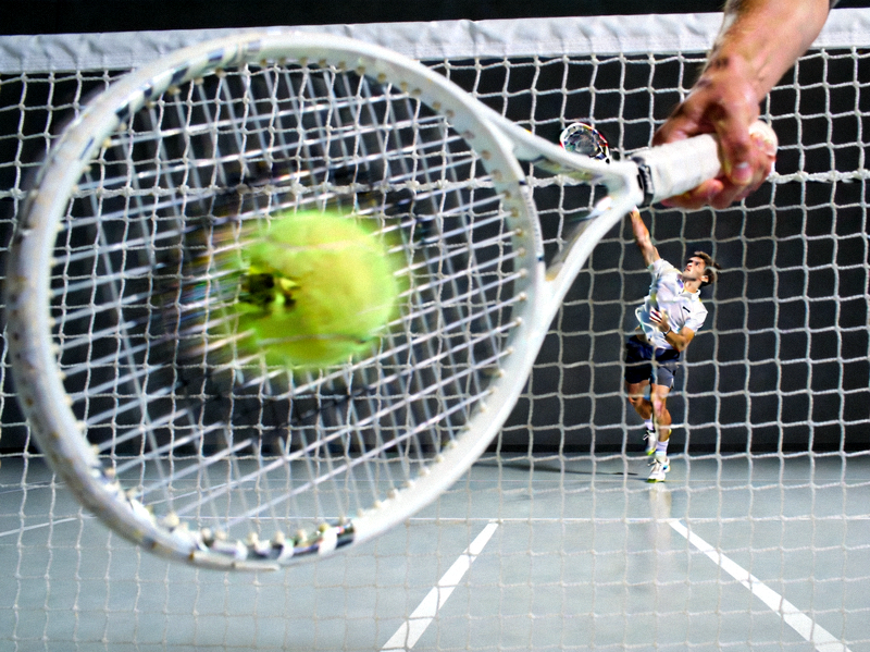 ATP网球大师赛，运动员在室内硬地球场发球瞬间，球拍挥动
